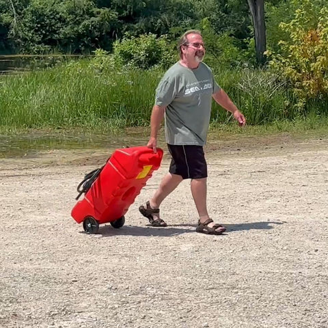 Man pulling Flo N Go 14 Gallon Gas Caddy On Wheels With 53 Liter Portable Fuel Tank And Built In 10 Foot Hose And Fuel Transfer Pump