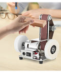 Compact Mini Electric Belt Sander, versatile desktop grinding machine for wood and metal polishing in use with wood piece.