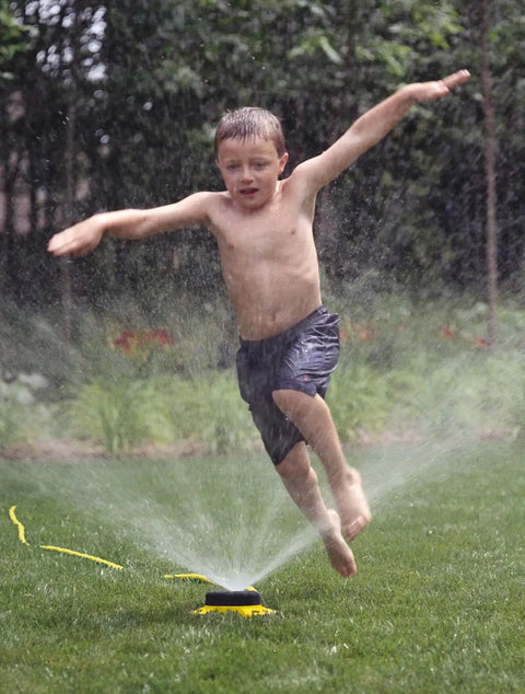 Child running through water from ColorStorm Nine Pattern Turret Sprinkler With Heavy Duty Metal Base Green 15024 For Lawn And Garden Watering