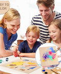 Front view of a family crafting with four 12x12 basswood sheets; kids and adults painting, inset shows a painted sample.