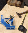 Heavy Duty Ductile Iron Welding Angle Clamp With 4.72 Inch Opening And 2.36 Inch Jaw Depth Powder Coated For Rust Resistance next to hammer and wood pieces.