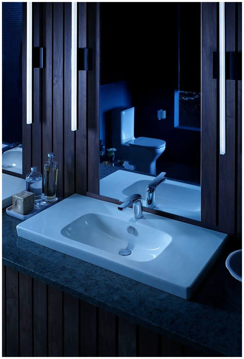 Modern bathroom with sleek sink and wooden accents, reflecting lighting details
