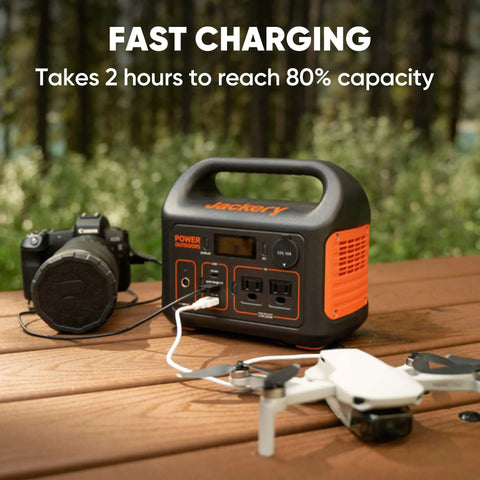 Portable Power Station Explorer 300 293Wh Backup Battery Solar Generator next to camera and drone on wooden table outdoors