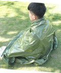 Person wrapped in olive green blanket from Three Piece Camping Survival Kit With Reflective Thermal Emergency Blanket And First Aid Gear