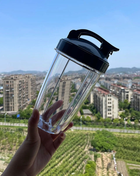 Hand holding Four Pack 32 Oz Blender Cups With Flip Top To Go Lids And Resealable Stay Fresh Lids Fit 600W And 900W Blenders