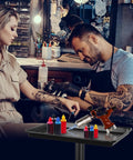 Tattoo artist using the Height Adjustable Rolling Salon Tray on Wheels with Multi Level Height Range from 28 to 44 Inches, black