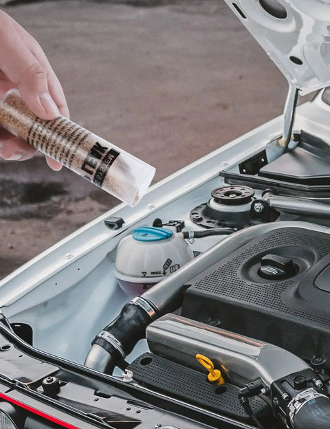Hand holding Radiator Stop Leak Sealer And Conditioner Kit For Cooling System Repair near open car engine
