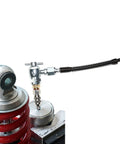 Front view of 5-piece nitrogen needle valve kit for shocks with Schrader valve and metal fittings on a red coil-spring suspension