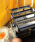 Level Up Your Kitchen Game With This No Sweat Hand Cranked Noodle Maker And Multi Function Dough Roller Press, silver, with dough and egg.