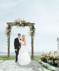 Sturdy 6.6Ft Wooden Garden Arbor Wedding Arch Backdrop Stand for Ceremony with couple under floral decorations by the sea