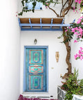 Turquoise hand carved door with rustic farmhouse vibe, surrounded by white walls and flowering vines, no glass or hardware included.