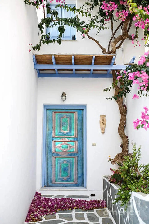 Turquoise hand carved door with rustic farmhouse vibe, surrounded by white walls and flowering vines, no glass or hardware included.