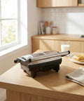 Elite Gourmet EPN-2976 2-in-1 Panini Press & Indoor Grill made from durable stainless steel on kitchen table.