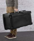 Person carrying the Flex Your Storage Game With Heavy Duty Plastic Footlocker Rolling Bin With Wheels And Handle, Stackable Tote Featuring Secure Latching Lid For Basements Dorms And Shared Spaces, Smooth Operator Hauler Chest In Black.