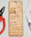 Wooden board with floral and cat engravings, red-handled pliers, and glue, featuring Dual Color Cloisonne Wire Set 20m Gold and Silver 0.3mm Thick Wire With 1mm Diameter Jewelry Making Tools Kit Includes Two Wire Straightening Boards for DIY Metalwork Home Decor Gift Crafting for Beginners and Pros