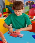 Child using Pink A5 Paper Cutter Guillotine with Side Ruler for Scrapbooking in a colorful classroom setting.
