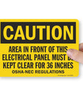 4 Pack OSHA Warning Stickers For Area In Front Of Electrical Panel Must Be Kept Clear For 36 Inches, yellow caution sticker held by hand