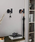 Four Pack Black Stainless Steel Towel Hooks Wall Mounted Heavy Duty Coat Robe Hanger For Door And Wall Use In Bathroom Bedroom Kitchen And Hotel Durable Waterproof Rustproof Modern Design Easy Drill Installation shown holding keys and umbrella