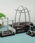 Two Pack Newtons Cradle Pendulum Desk Toy With Five Balance Balls Gravity Ball Office Decor on a blue surface with plant