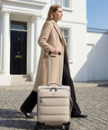 Woman walking with Underseat Carry On Luggage With Smooth Spinner Wheels, Lightweight Softside Suitcase For 2 Day Travel, beige color
