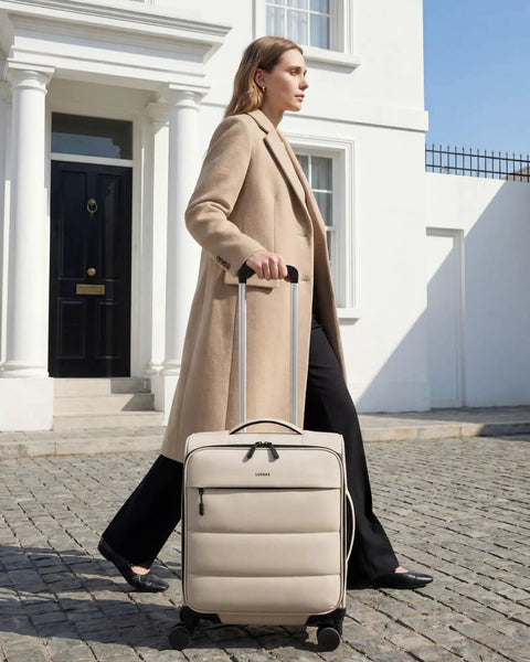 Woman walking with Underseat Carry On Luggage With Smooth Spinner Wheels, Lightweight Softside Suitcase For 2 Day Travel, beige color