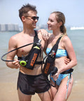 Couple holding Ultra Compact 1L Portable Scuba Tank with Gauge for snorkeling on beach, showcasing 75 breaths at 200 bar kit.