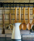 Barista Grade Coffee Grinder Cleaning Brush with natural boar bristles and walnut handle hanging on a kitchen rack.
