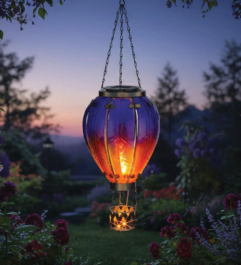 Purple Solar Hot Air Balloon Lantern Hanging LED Lit Outdoor Light For Garden Patio And Pathway Waterproof Portable Decorative Lamp Made Of Metal And Glass illuminating a garden at dusk.