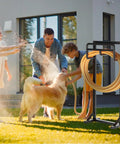 Family using heavy duty freestanding garden hose holder with stable base and tool hooks in black finish on lawn
