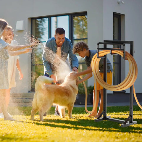 Family using heavy duty freestanding garden hose holder with stable base and tool hooks in black finish on lawn