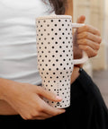 40oz Polka Dot Insulated Tumbler Featuring A Spill Proof Flip Straw And Comfort Grip Handle being held, white with black polka dots.