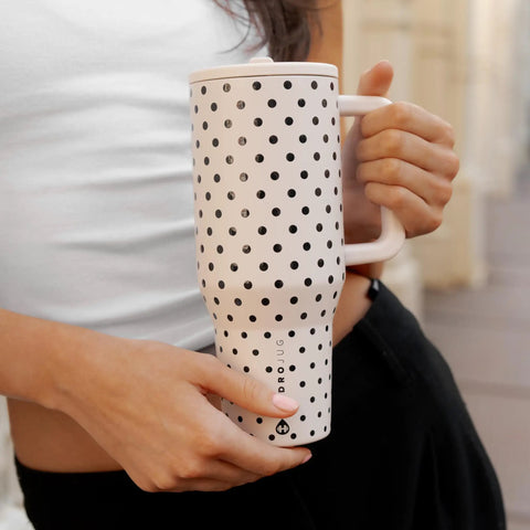 40oz Polka Dot Insulated Tumbler Featuring A Spill Proof Flip Straw And Comfort Grip Handle being held, white with black polka dots.