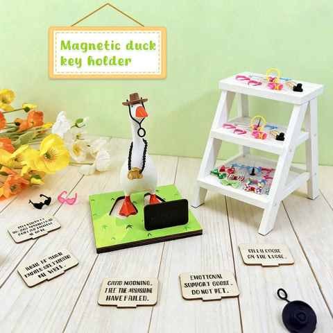 Goose Key Holder Desk Statue With Magnetic Base And Fashion Accessories Pack Hats Bow Ties Necklaces Headphones Chalkboard Cap For Home Office Decor And A Fun New Apartment Housewarming Gift displayed with accessories on a green base