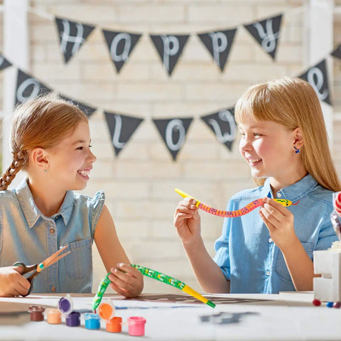 Girls painting snakes from Ten Piece Unfinished Wooden Snakes Craft Kit With Jointed Wiggly Bodies, includes paint and brushes.