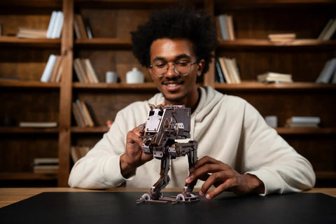 Person assembling a Wooden Star Wars AT ST Walker 3D Puzzle Featuring Smooth Shifting Gear System That Delivers Real Walking Motion.