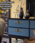 Blue cabinet with ornate drawer pulls in living room setting, featuring vases and decorative screen in background.