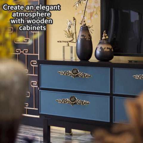 Blue cabinet with ornate drawer pulls in living room setting, featuring vases and decorative screen in background.