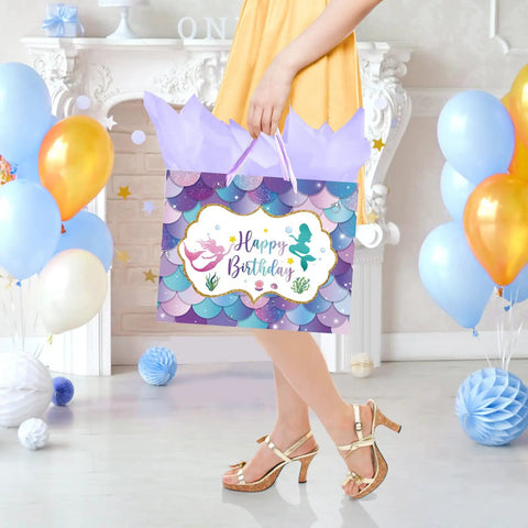 Woman holding a 13 Inch Mermaid Birthday Gift Bag With Handle For Kids Party, Purple Gift Bag With Tissue Paper And Card Included in festive setting.