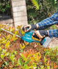 Person using 18V LXT Cordless Grass Shear With Hedge Trimmer Blade, 2-In-1 Quick Blade Change, Tool Only, Renewed, on shrub.