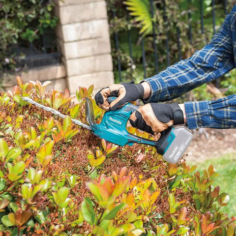 Person using 18V LXT Cordless Grass Shear With Hedge Trimmer Blade, 2-In-1 Quick Blade Change, Tool Only, Renewed, on shrub.