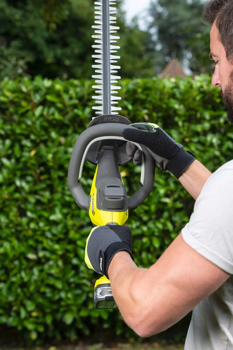 Pro Level 18V ONE PLUS Cordless Hedge Trimmer Featuring 55cm Double Edge Blades, ergonomic grip in use against greenery.