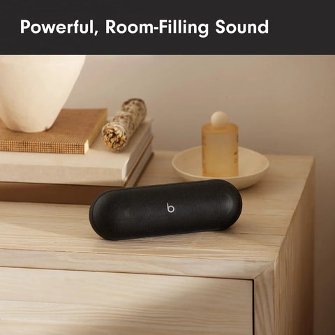 Matte black portable Bluetooth speaker with up to 24 hours of battery life, water resistant, on wooden shelf indoors.