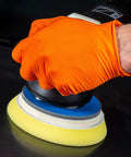 Orange nitrile gloves with diamond-textured grip; close-up of hand using a polisher.