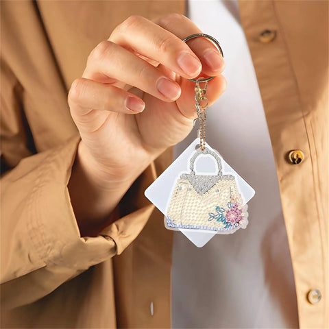 Six Piece Double Sided Diamond Painting Keychain Kit Set For Beginners And Adults held by a hand, featuring a bag ornament.