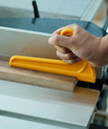Hand using yellow push stick for table saw, ensuring safety while cutting wood. Heavy Duty Push Block And Push Stick Set For Table Saws Router Tables Band Saws Delivers Smooth Handling And Slays Kickback Dead In Its Tracks On Every Cut.