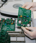 Engineer inspecting circuit board under magnifier in electronics lab
