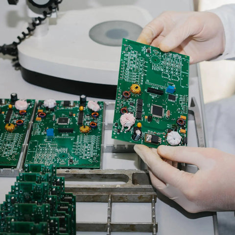 Engineer inspecting circuit board under magnifier in electronics lab