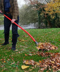 Person using Heavy Duty Garden Rake That Slays Leaves And Debris With Ease Sturdy Tines Do Not Bend Under Pressure on fall leaves.