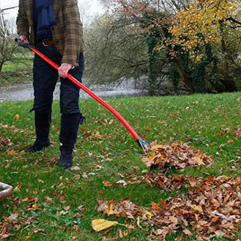 Person using Heavy Duty Garden Rake That Slays Leaves And Debris With Ease Sturdy Tines Do Not Bend Under Pressure on fall leaves.