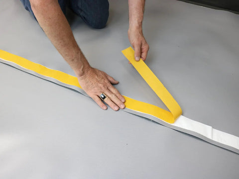 Person applying moisture shield tape on Premium Underlayment For Luxury Vinyl Laminate And Hardwood Floors Beat The Noise Sound Pad.